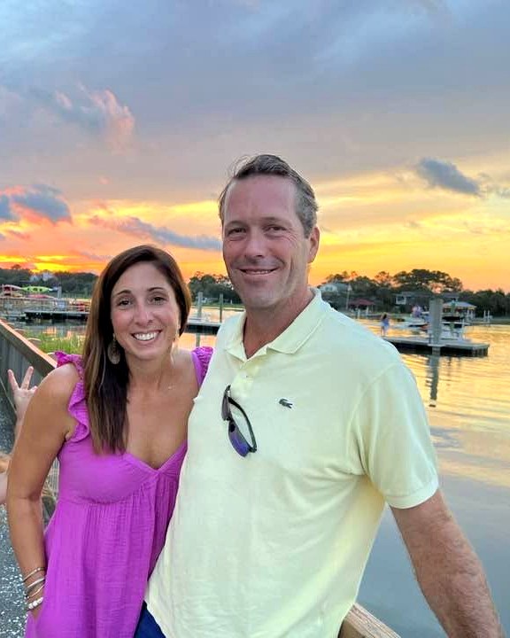 Greg Loeffelholz and his wife by the waterfront at sunset